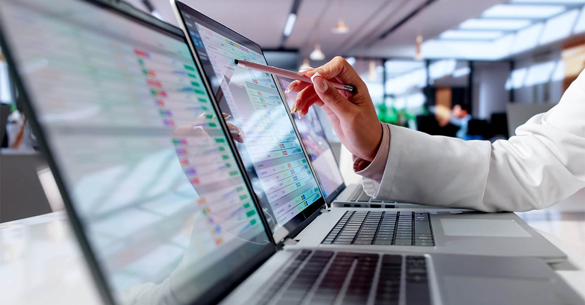 Healthcare professional reviewing digital medical records on multiple laptop screens, illustrating medical coding and billing analysis.